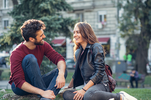 Happy couple talking while sitting on a meadow